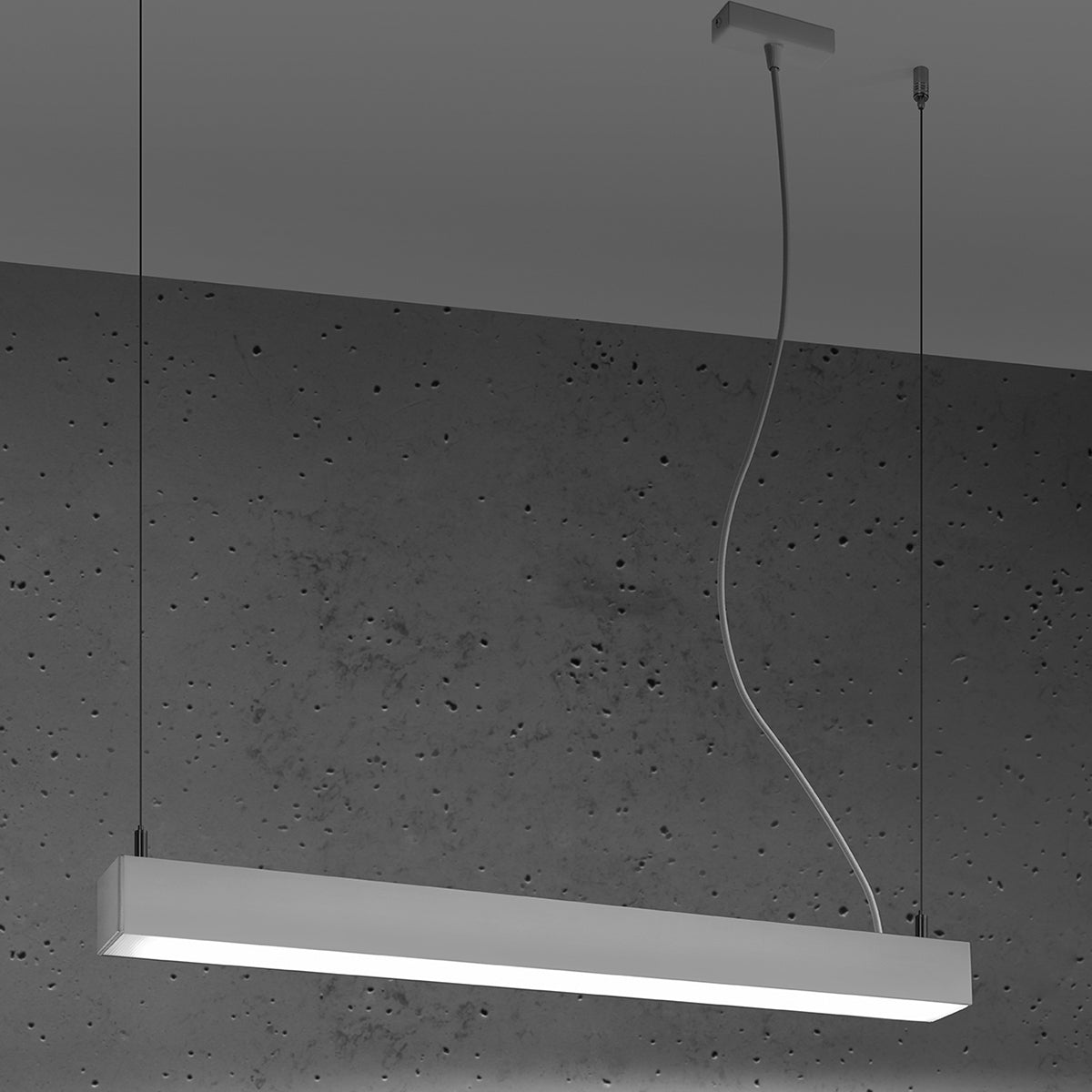 Le luminaire allumé éclaire la pièce, fixé au plafond par câbles.