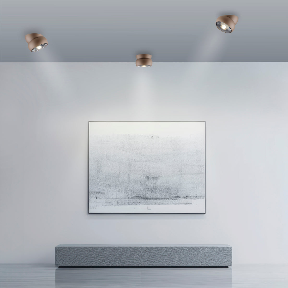 Mise en ambiance de trois plafonniers marron éclairant un mur blanc et un cadre.