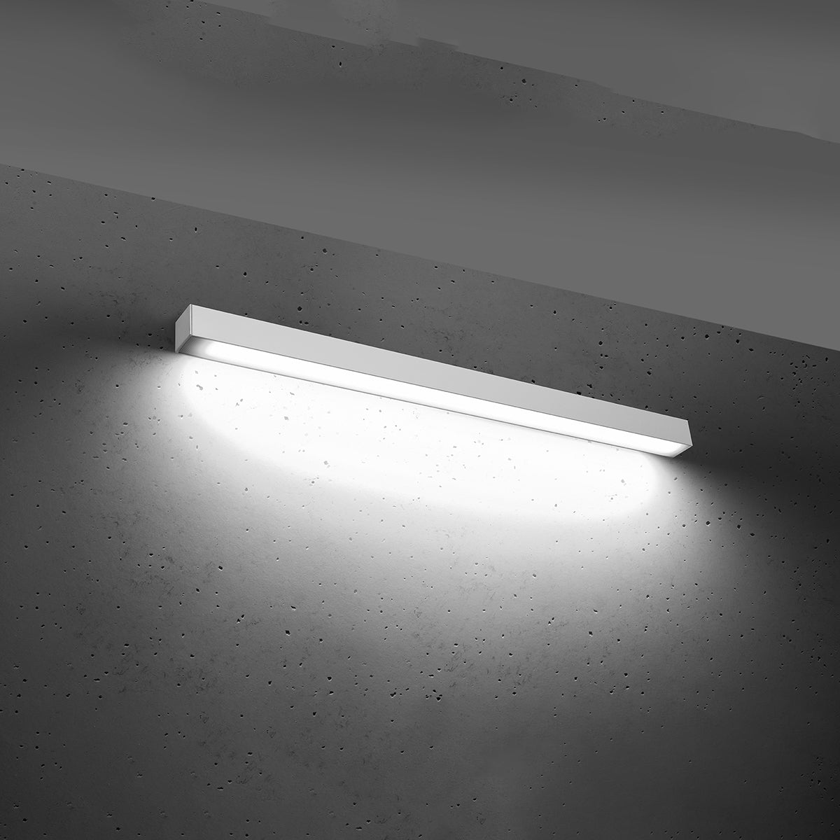 Mise en ambiance, applique allumée projetant un halo sur béton gris