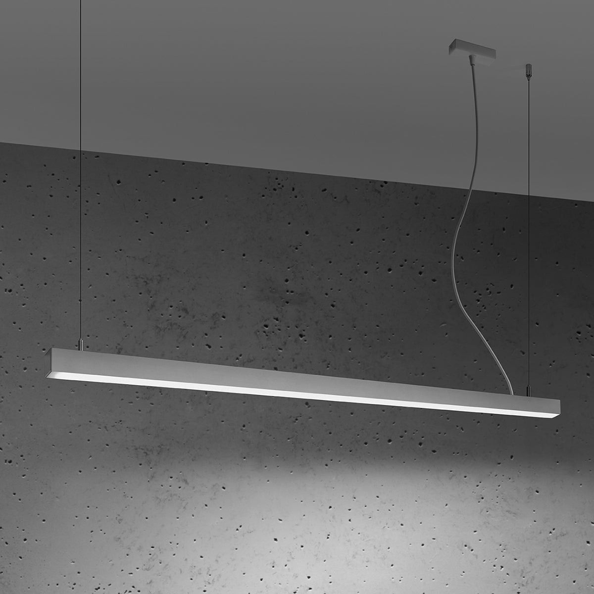 Luminaire allumé en ambiance, bandeau blanc projetant sa lumière sur le béton