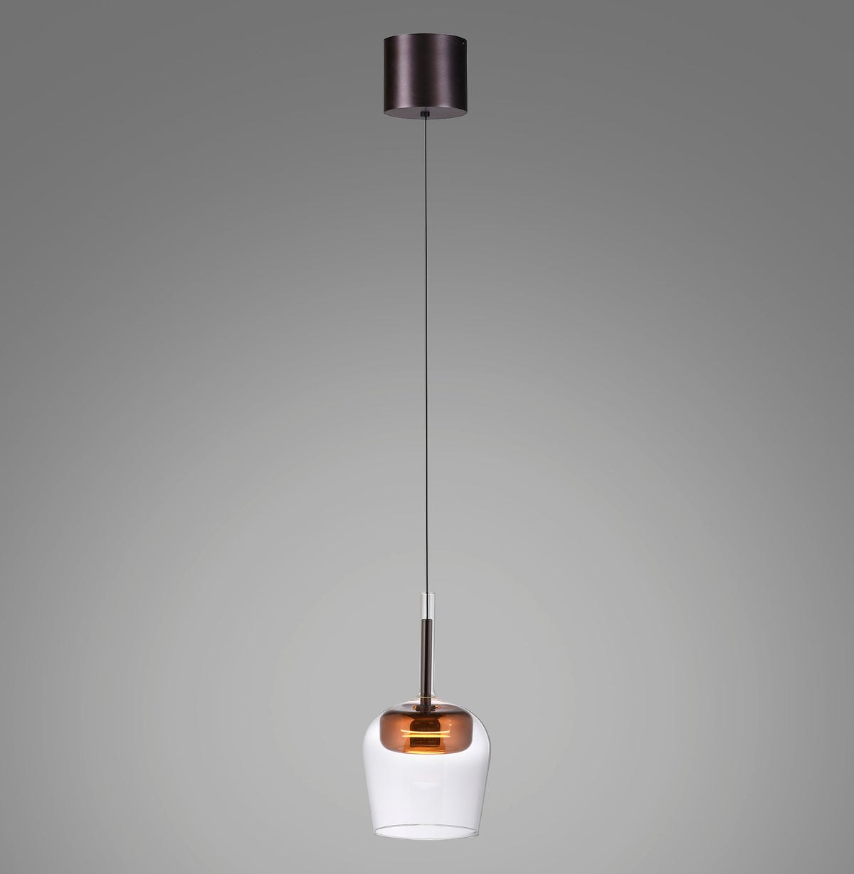 Suspension seule allumée, verre transparent et calotte cuivrée, câble fin sur fond gris.