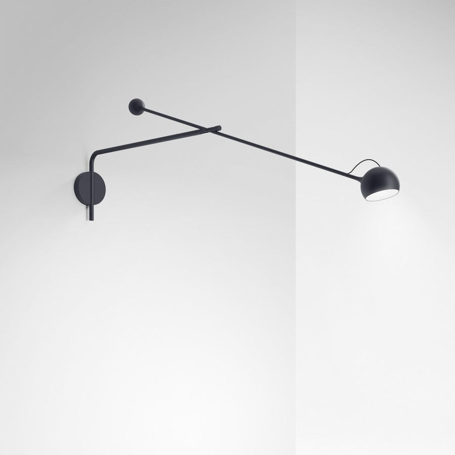 Applique murale anthracite fixée sur un mur blanc, long bras orientable et diffuseur.