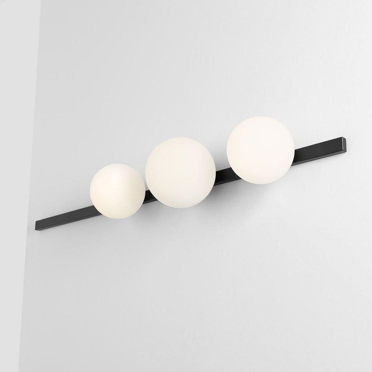 Détail de l'applique murale fixée au mur, montrant les trois globes allumés.