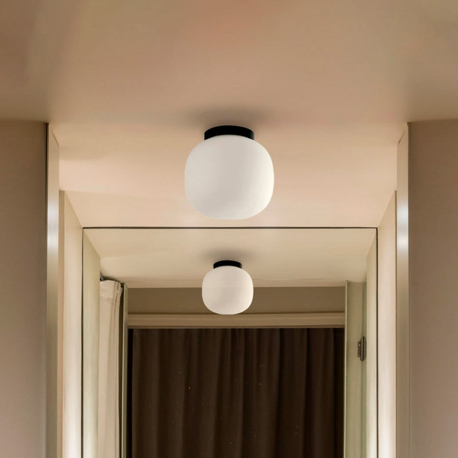 Plafonnier allumé au plafond d’un couloir, reflet dans un miroir vertical.