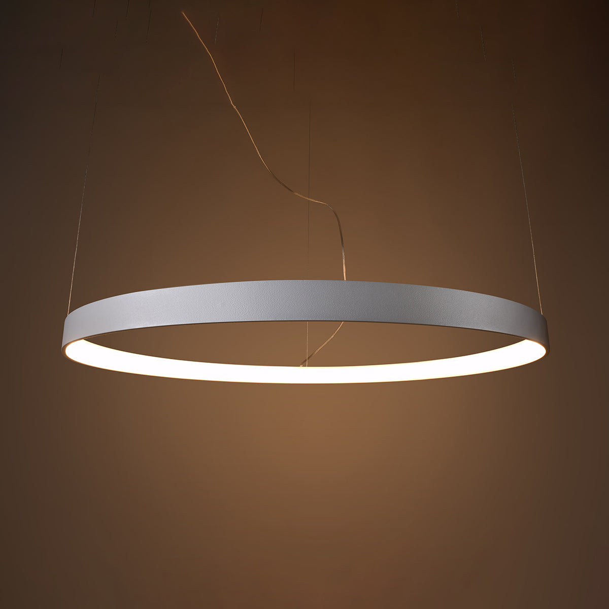 Mise en ambiance du luminaire allumé, halo chaud sur mur brun