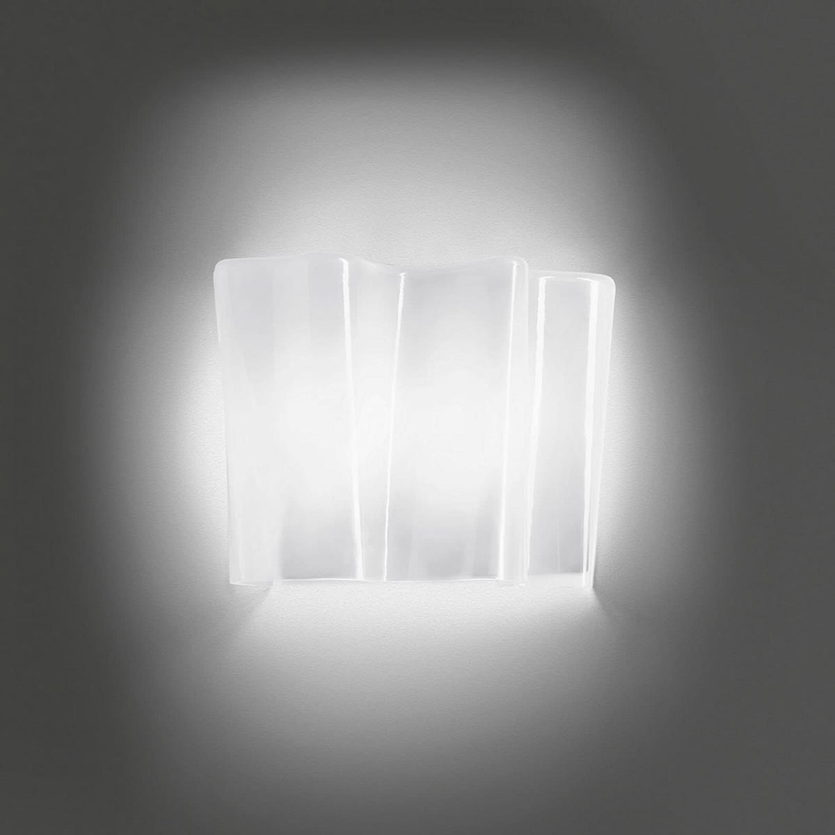 Vue de face de l’applique allumée, halo lumineux diffus sur le mur.