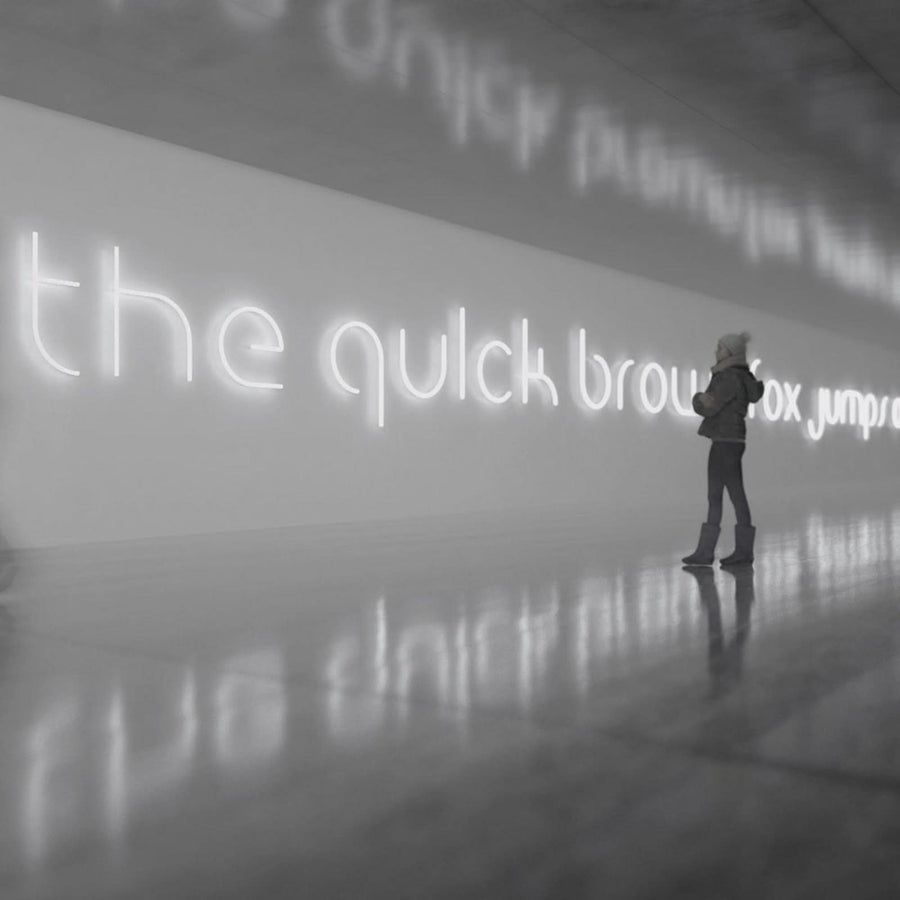 Une femme contemple une longue phrase lumineuse blanche reflétée sur le sol