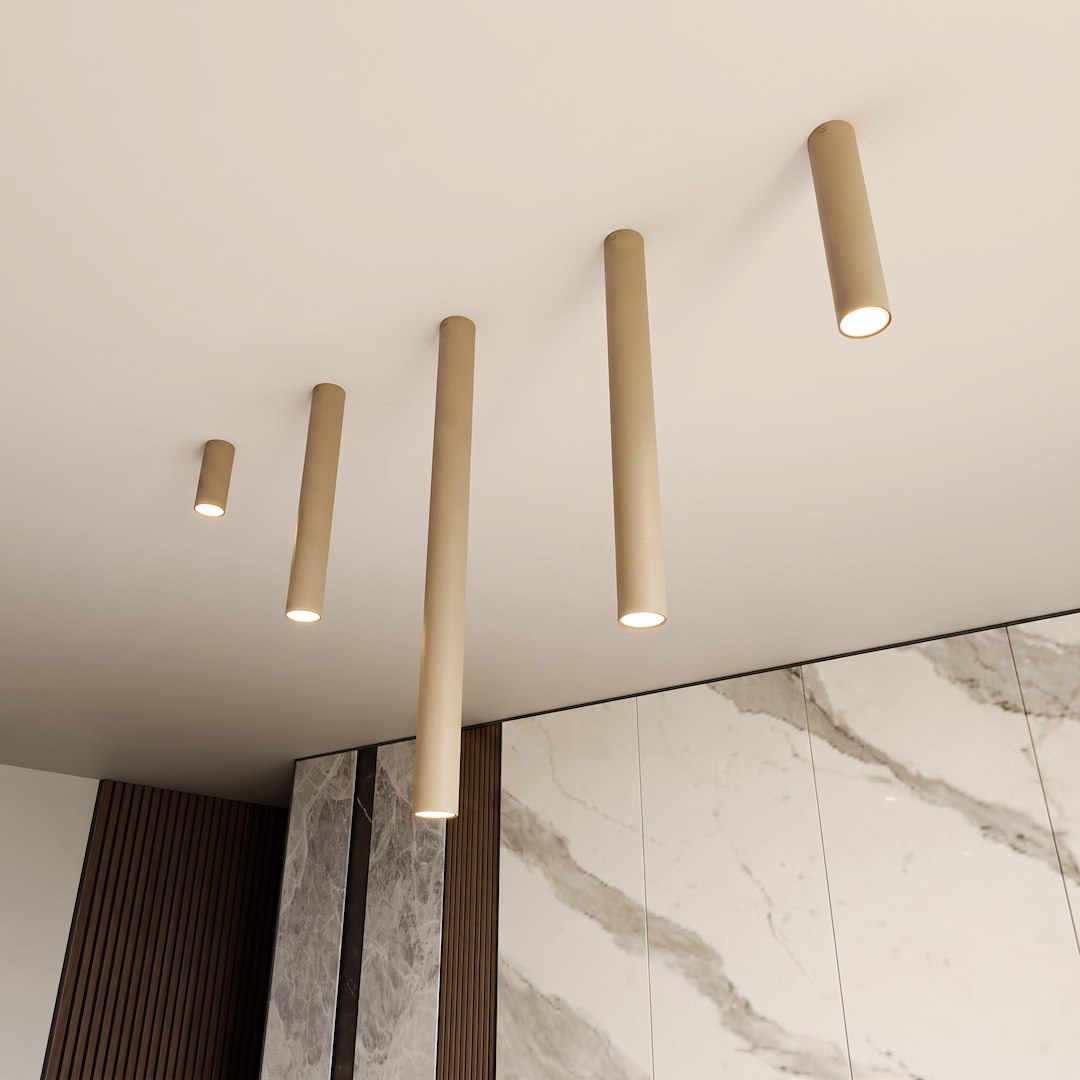 Cinq tubes beige de longueurs différentes au plafond, devant un mur de marbre veiné.