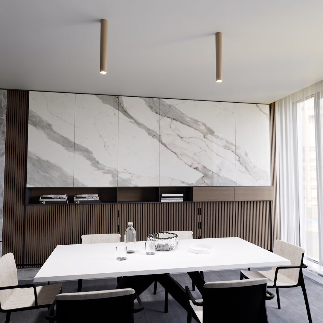 Mise en ambiance : deux plafonniers cylindriques au-dessus d'une table de salle à manger blanche.