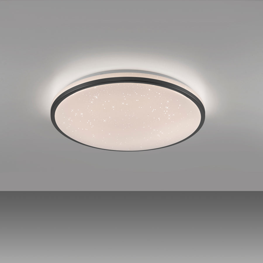 Plafonnier rond installé au plafond dans une pièce grise, lumière allumée.