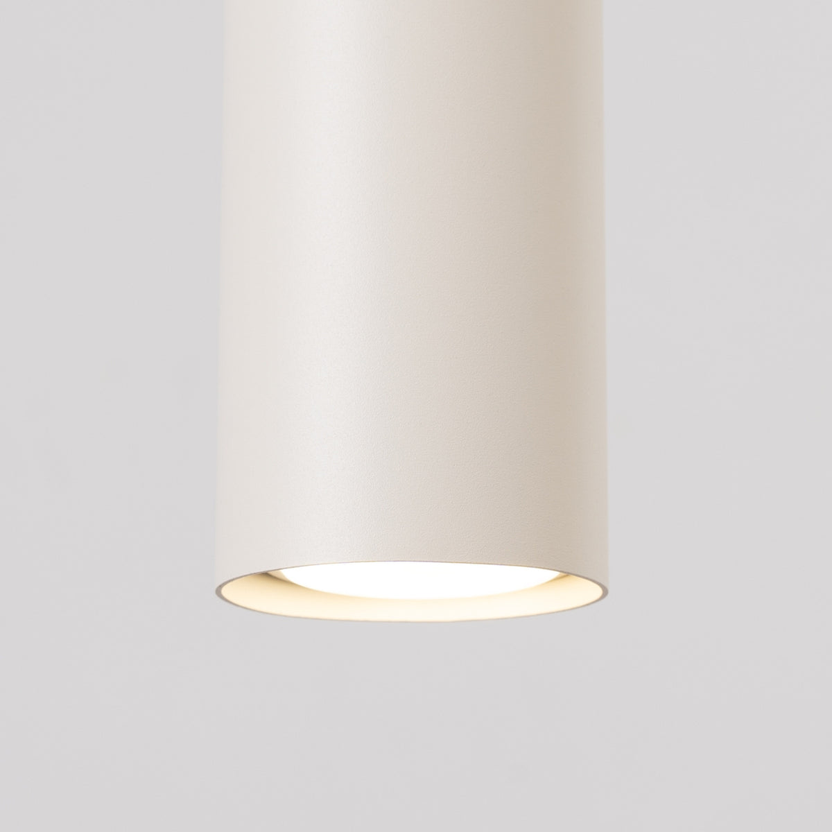 Détail du bas d'un cylindre allumé avec diffuseur blanc et halo lumineux.