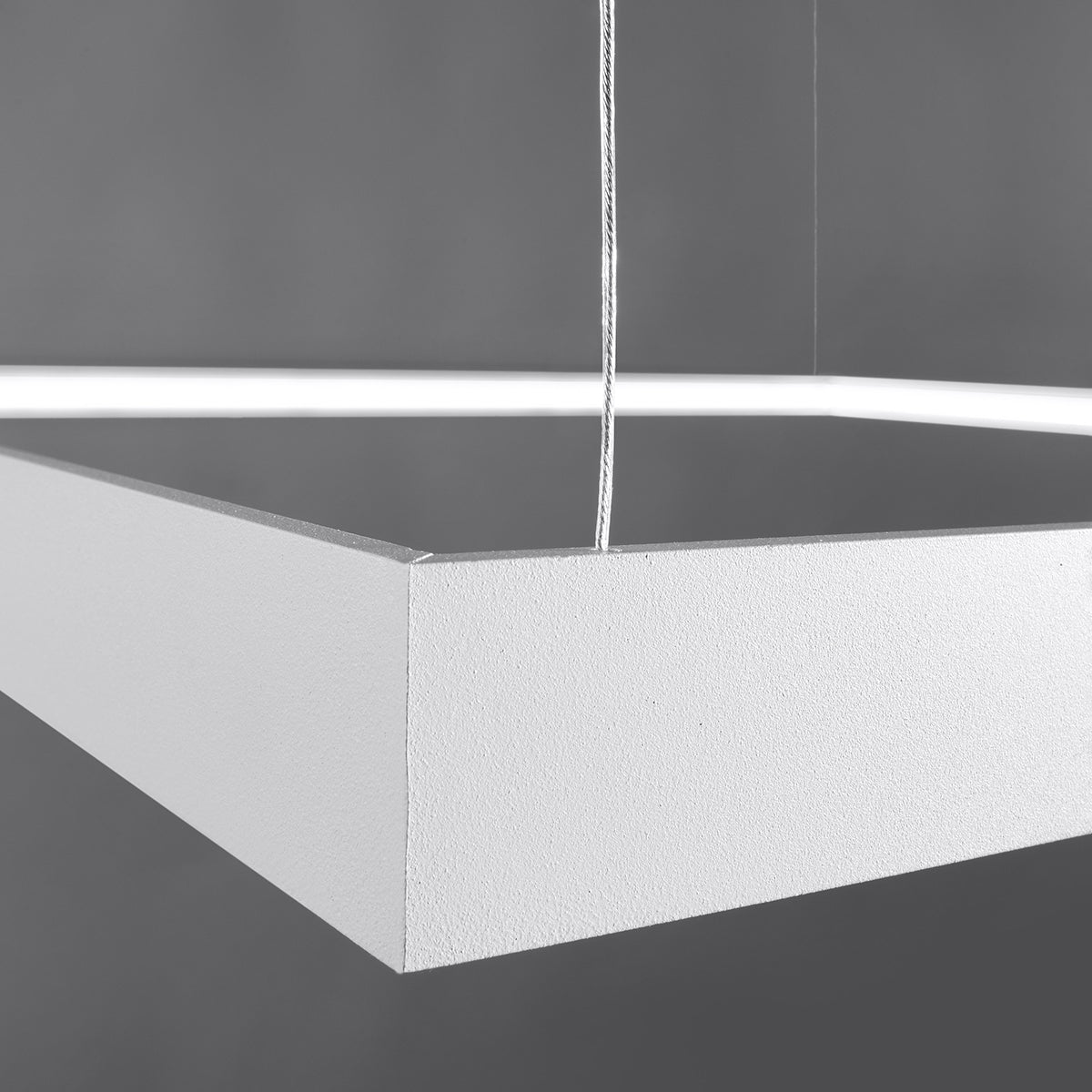 Détail rapproché d'un angle du cadre blanc et du câble de suspension tressé.