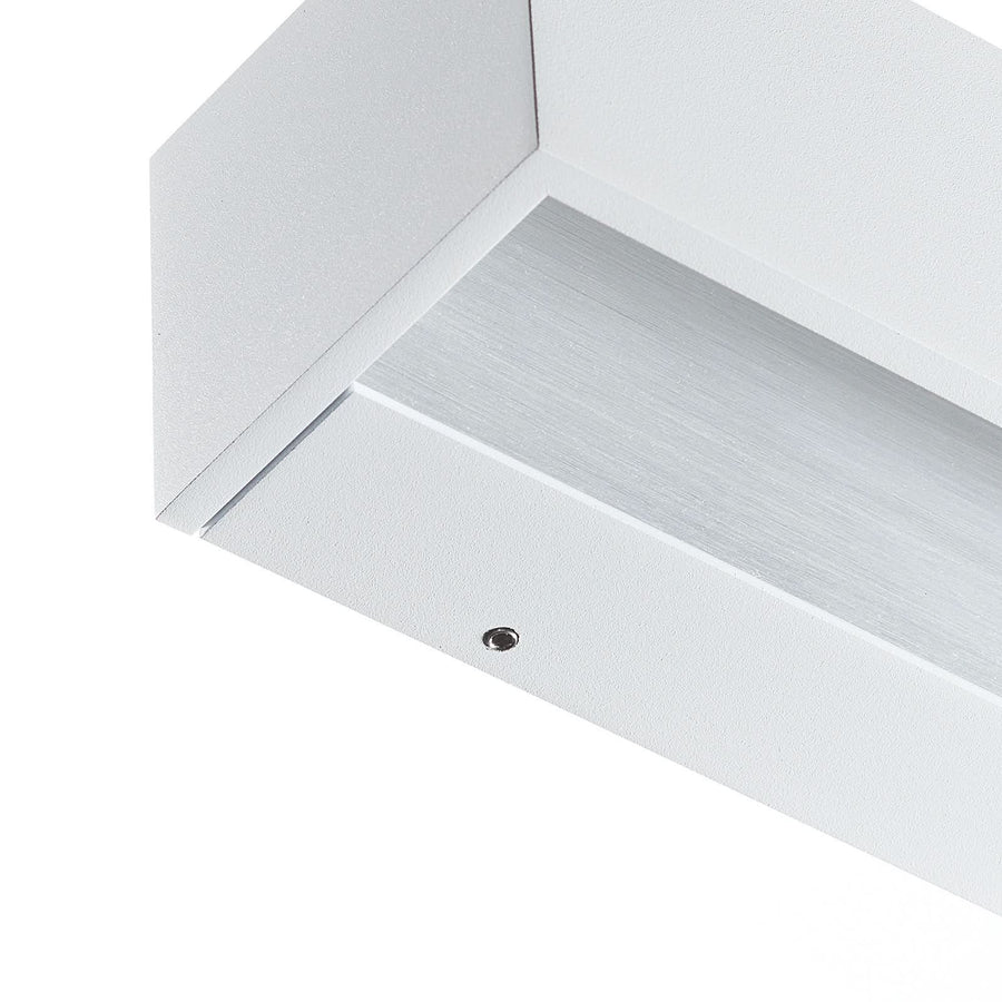Détail de l'angle en aluminium blanc, vis apparente et diffuseur brossé strié.