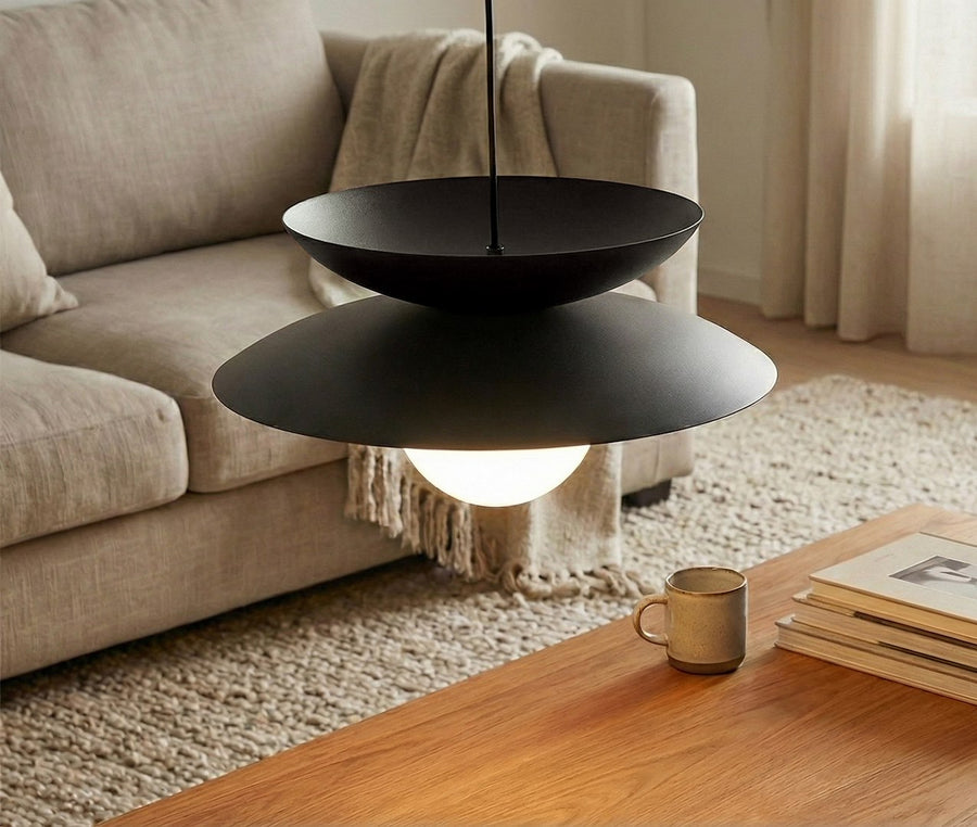 Mise en ambiance dans un salon, suspension noire au-dessus d'une table en bois