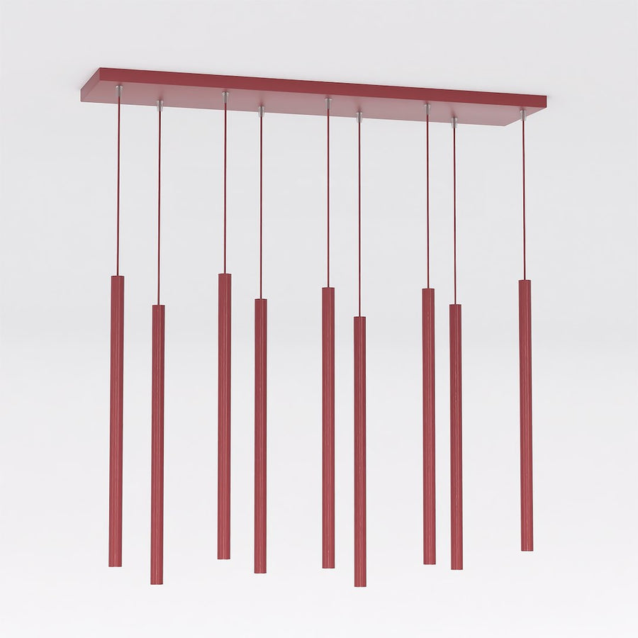 Luminaire de face sur fond blanc, neuf tubes cylindriques bordeaux suspendus à hauteurs décalées.