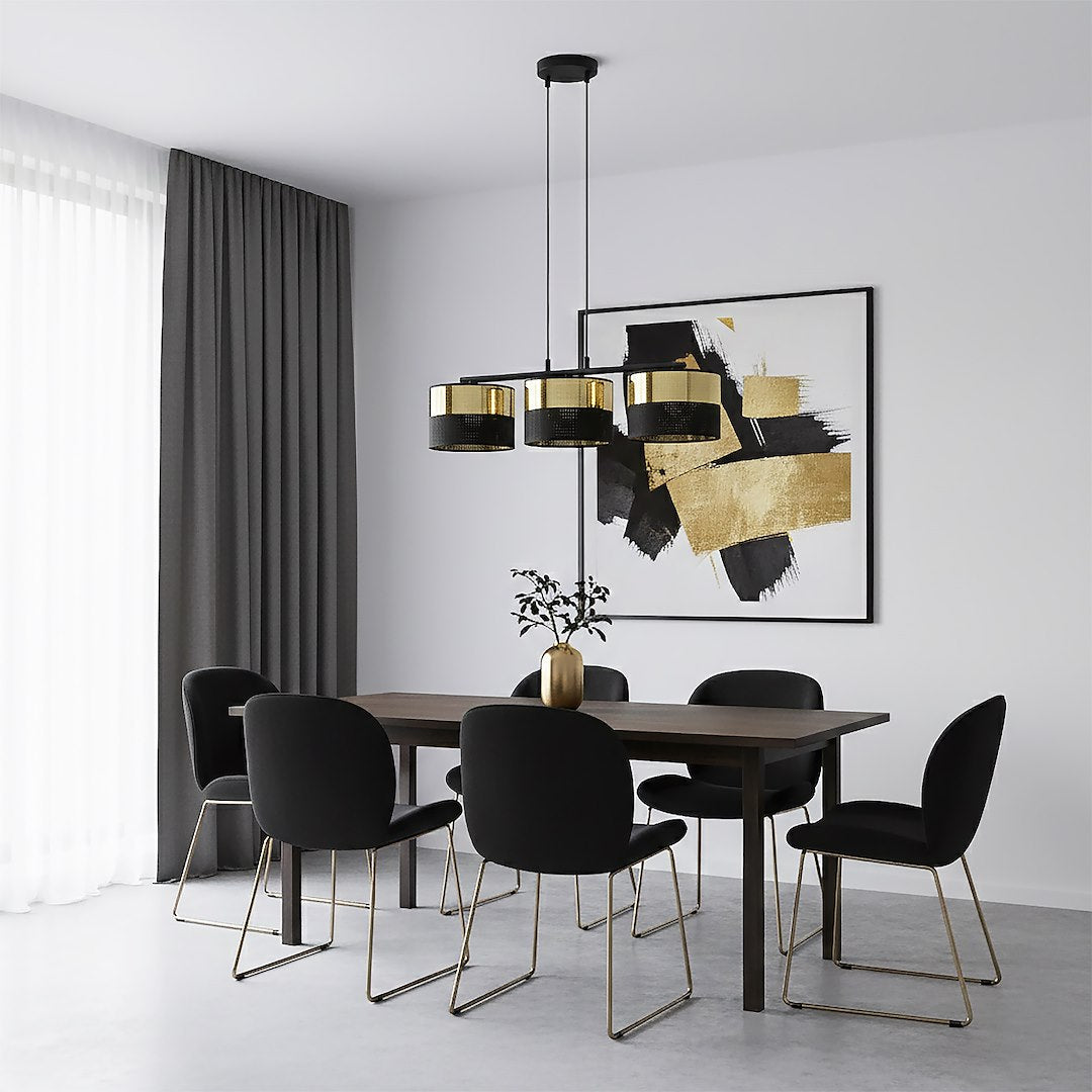 Mise en ambiance salle à manger sombre, luminaire doré suspendu au-dessus d'une table en bois.