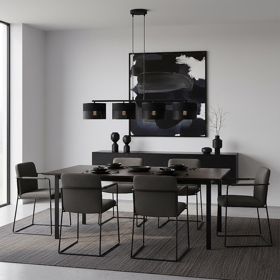 Grande pièce à vivre avec table noire, tableau abstrait et luminaire suspendu éclairé.