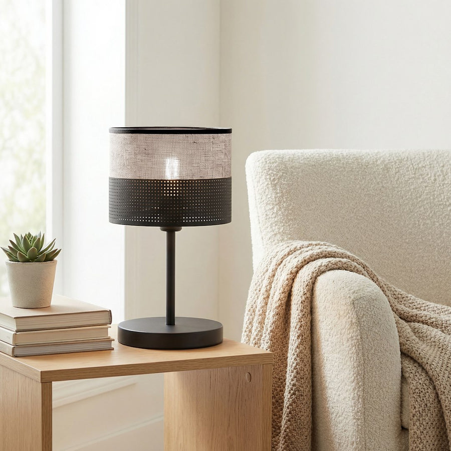Lampe éclairée posée sur une table en bois, près d'un fauteuil crème