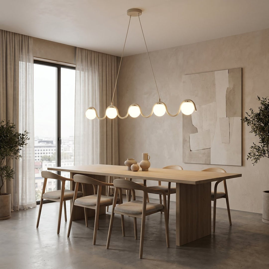 Suspension éclairée au-dessus d'une longue table en bois, grande pièce claire