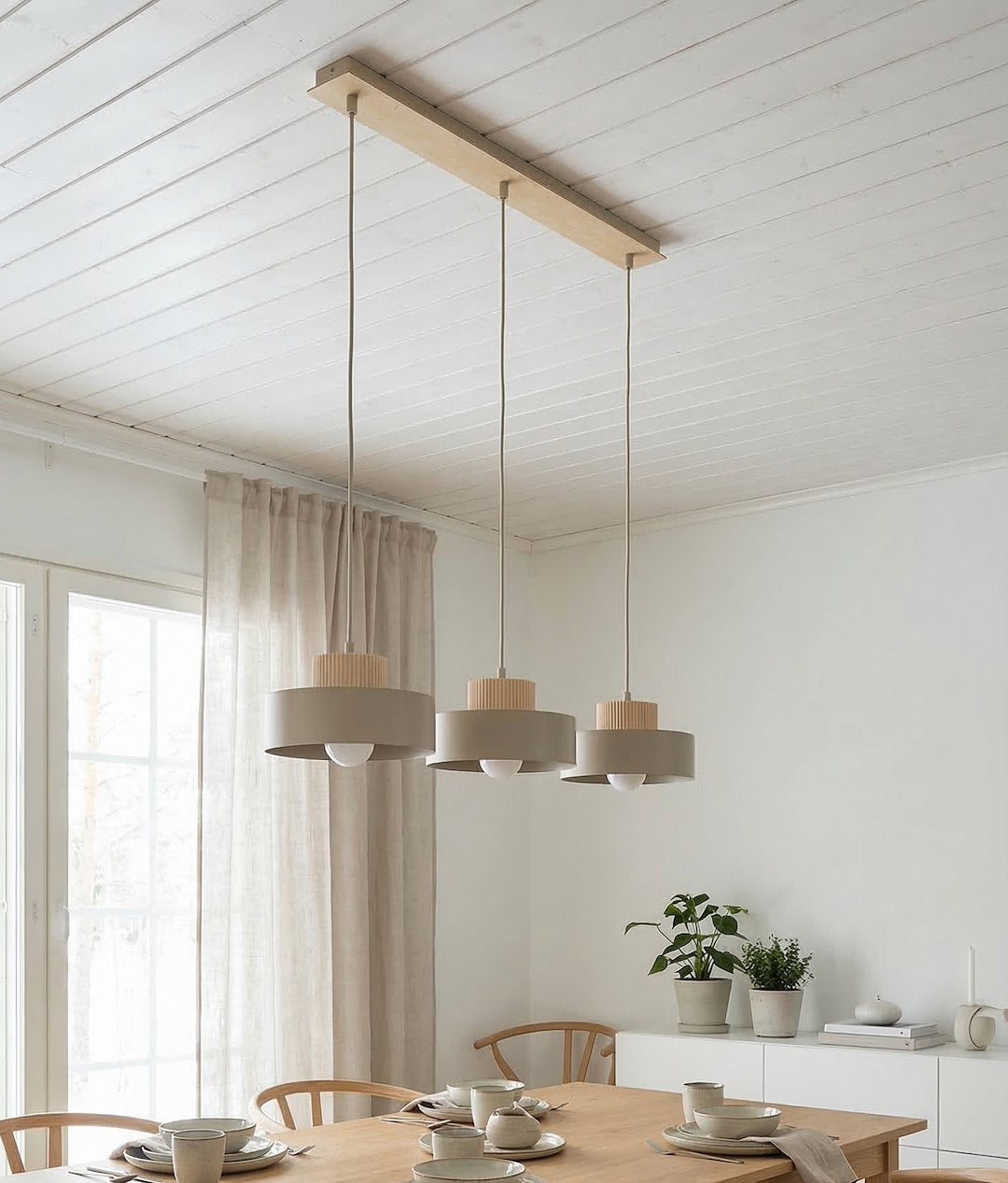 Vue en situation dans un intérieur blanc, suspension au-dessus d'une table dressée près de la fenêtre.