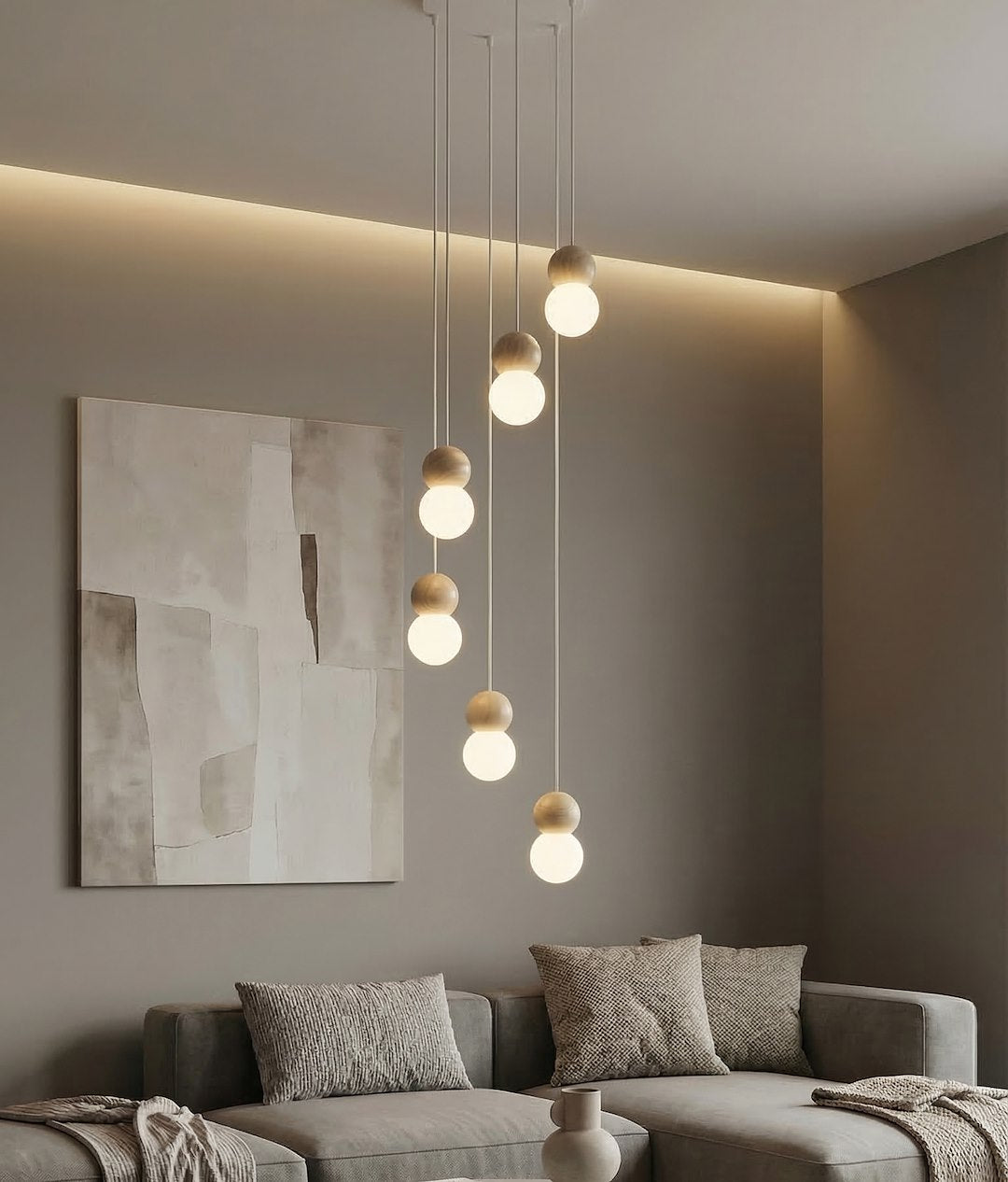 Luminaire suspendu éclairé au-dessus d'un canapé gris, tableau abstrait au mur