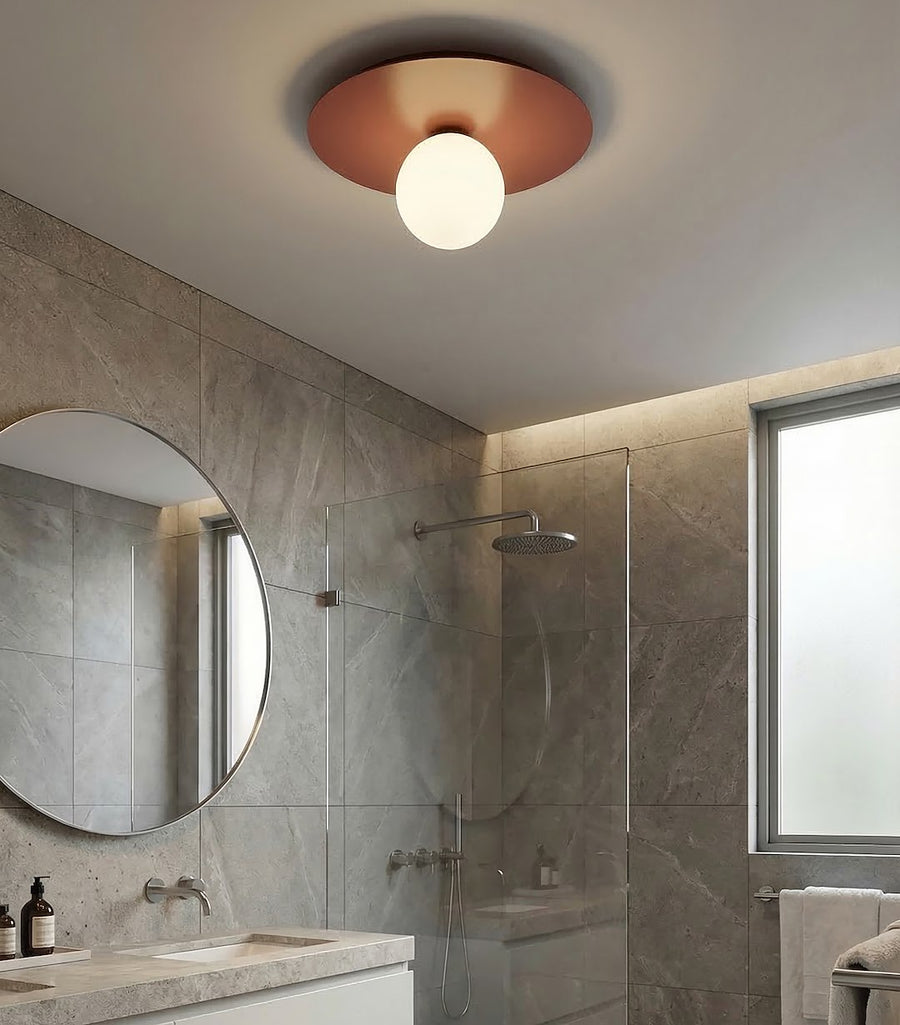 Plafonnier installé dans une salle de bain carrelée, près d'un miroir rond