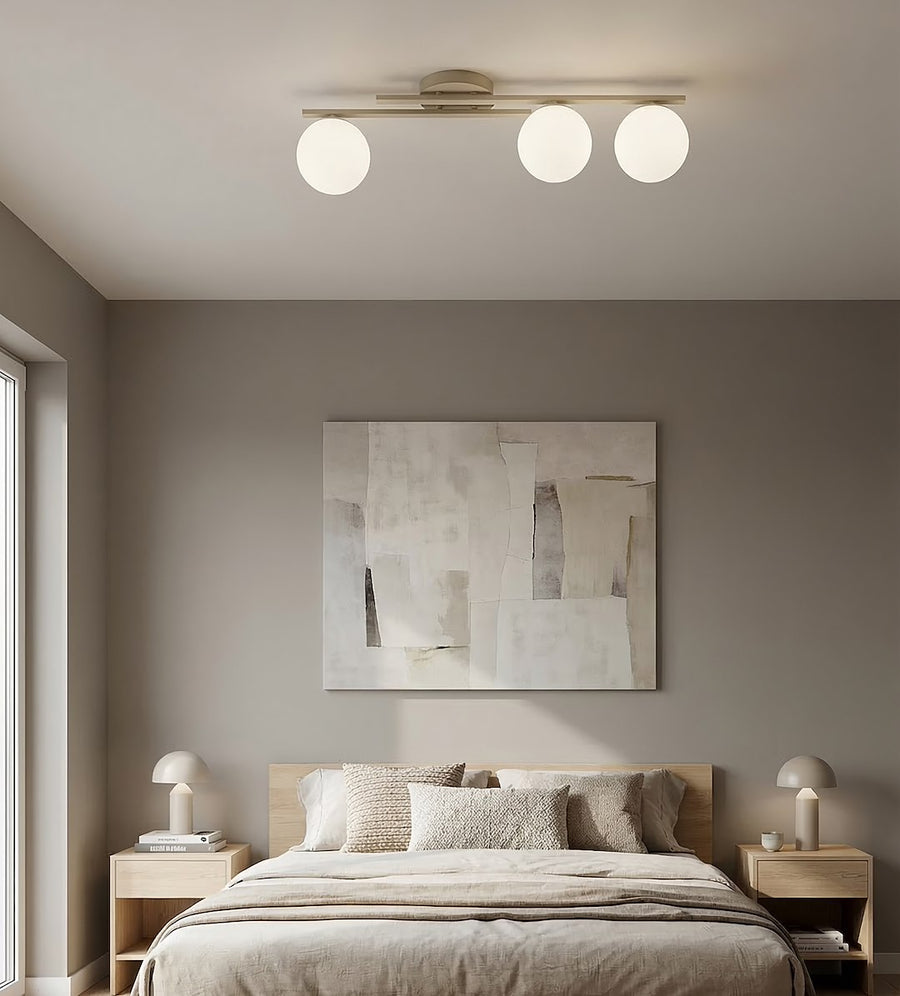 Mise en ambiance chambre grise avec lit, plafonnier allumé au-dessus du tableau