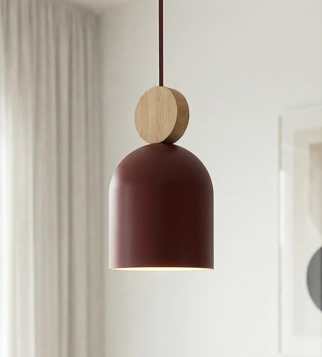 Détail rapproché d'une cloche bordeaux et de sa bille en bois clair.