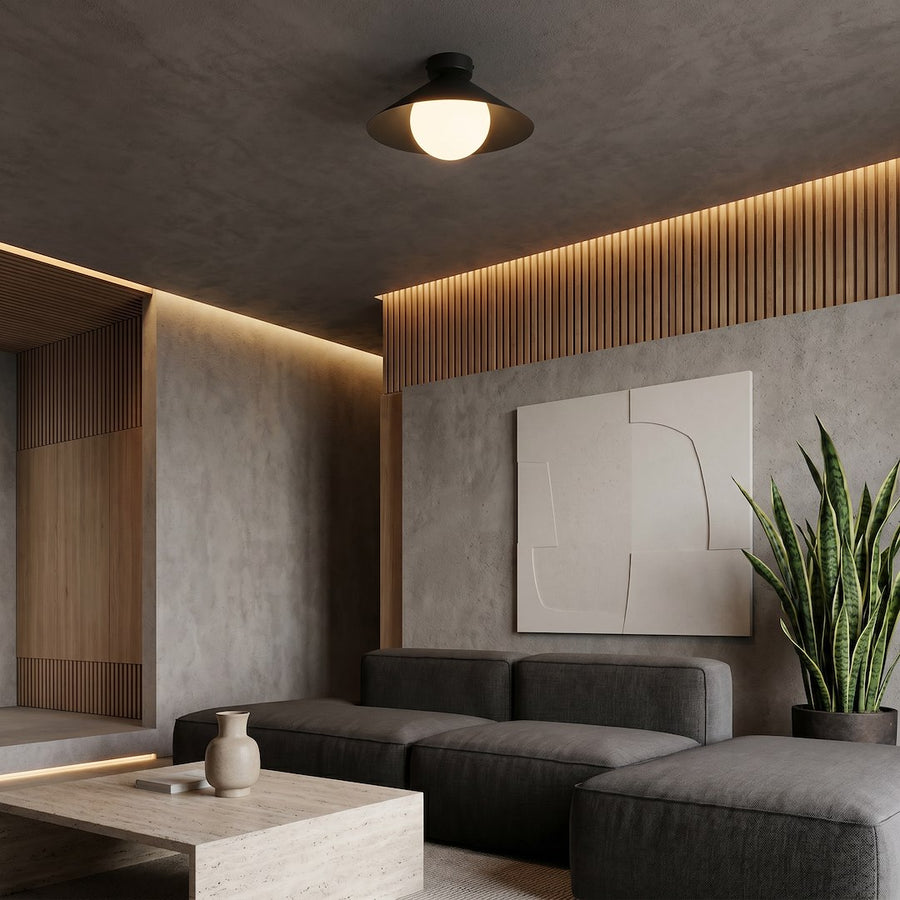 Mise en scène intérieure sombre, plafonnier allumé au-dessus d'un salon béton.