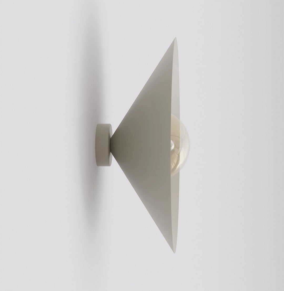 Vue de profil de l’applique beige, cône orienté vers le haut, ampoule ambrée visible.