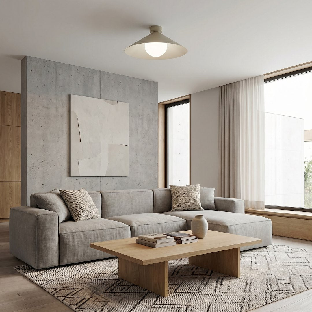 Mise en ambiance dans un salon contemporain, plafonnier beige allumé au-dessus d'un canapé gris.