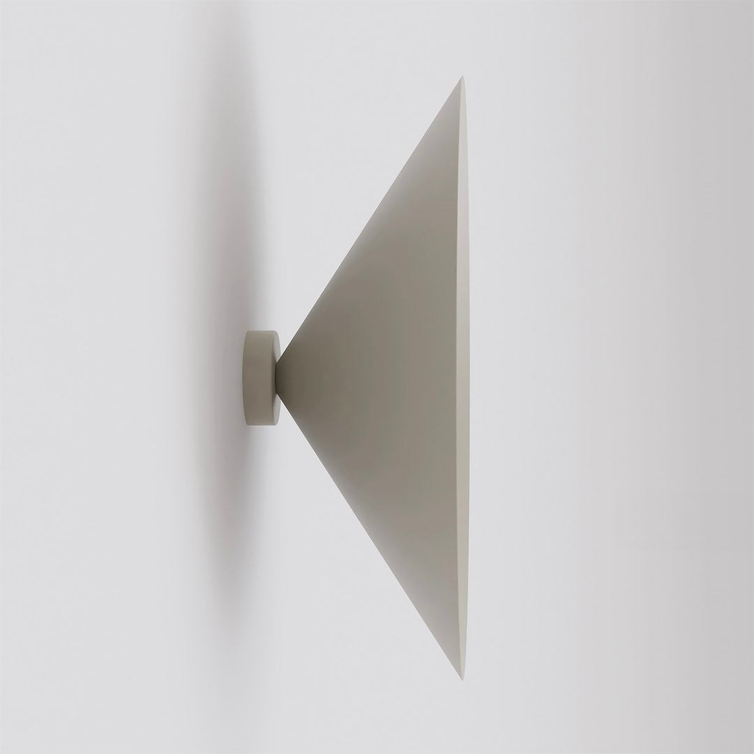Vue de profil d'une applique murale beige en forme de cône sur mur blanc.