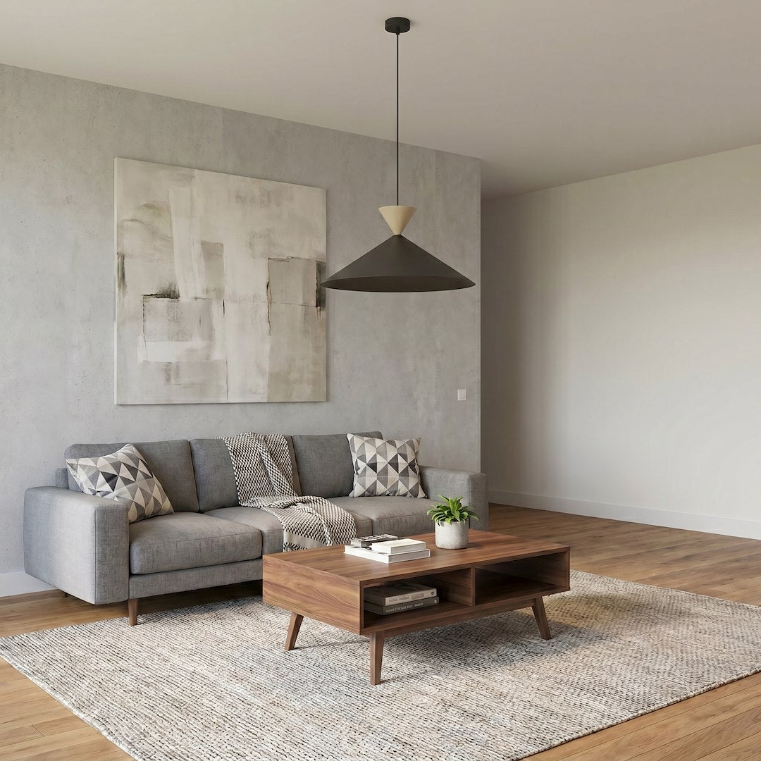 Luminaire suspendu éclairant un salon avec canapé gris et table basse