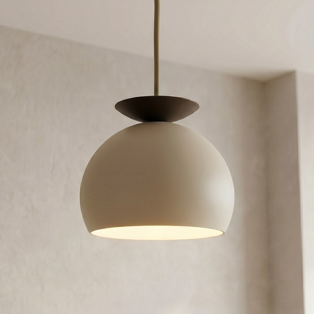 Gros plan sur l'abat-jour bombé beige et le disque supérieur noir de la suspension.