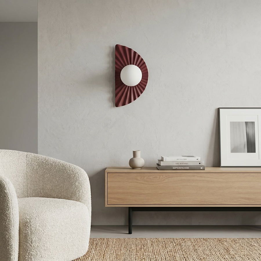 Vue d'ensemble d'un salon avec l'applique bordeaux fixée au mur et un canapé.