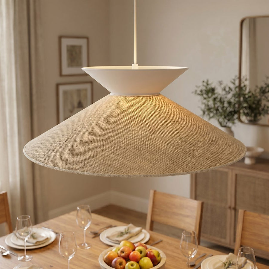 Gros plan sur l'abat-jour en rotin tissé et la lumière chaude au-dessus d'une table dressée.