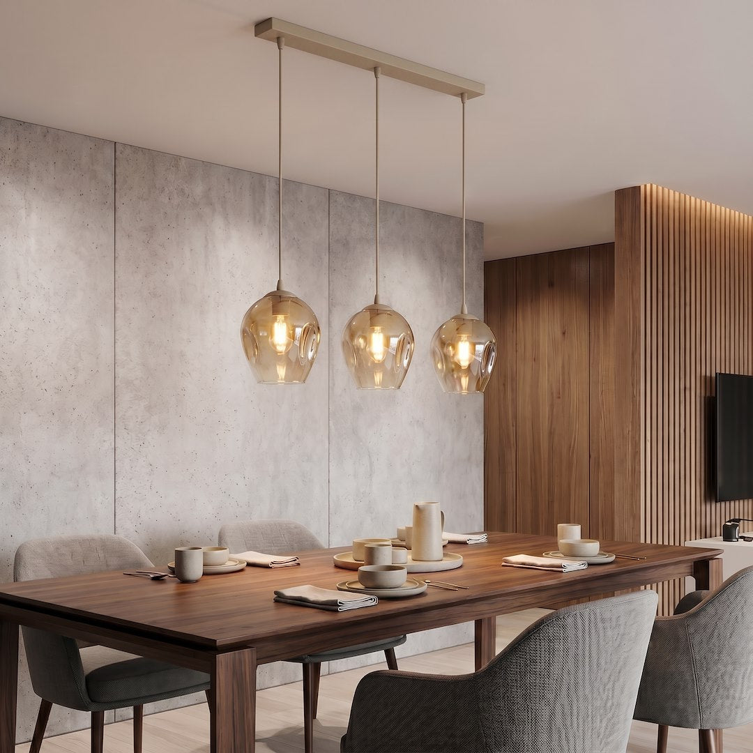 Mise en ambiance au-dessus d'une table à manger, suspension triple en verre ambré allumée.
