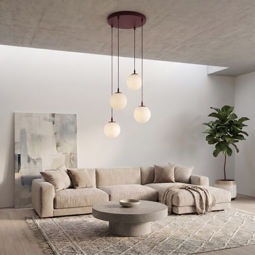 Mise en ambiance dans un salon, suspension bordeaux éclairée au-dessus d'un canapé beige