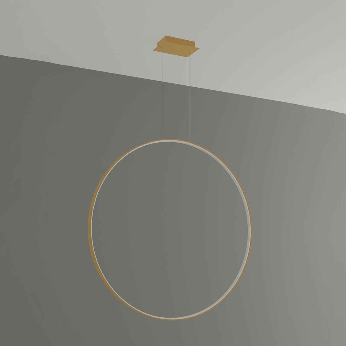 Luminaire suspendu en anneau doré, éteint, présenté sur fond gris uni.