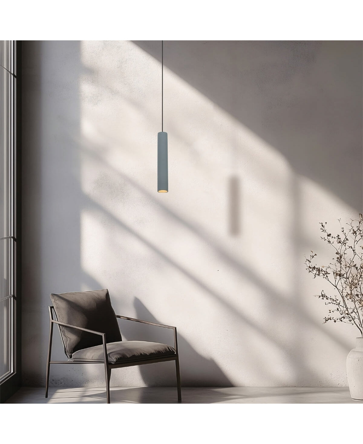 Mise en ambiance avec fauteuil en cuir, vase et branches séchées sous la suspension grise