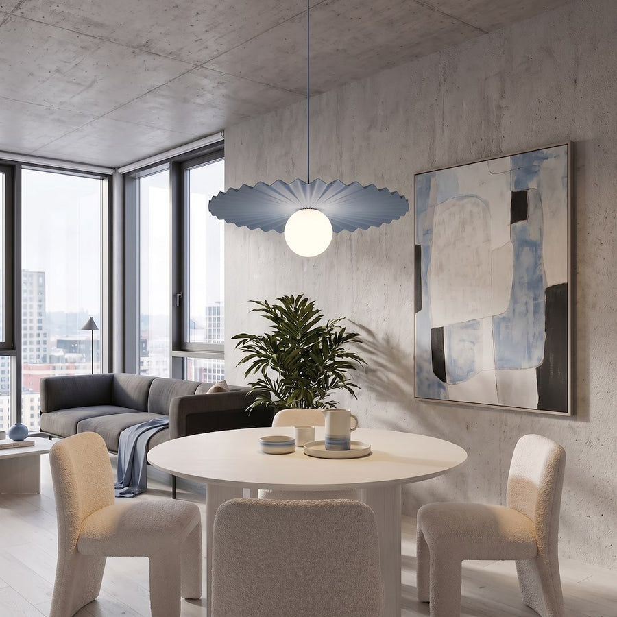 Suspension bleue plissée dans un intérieur béton, au-dessus d'une table blanche.