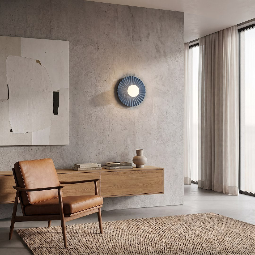 Ambiance salon contemporain, applique murale bleue sur mur béton, fauteuil en cuir