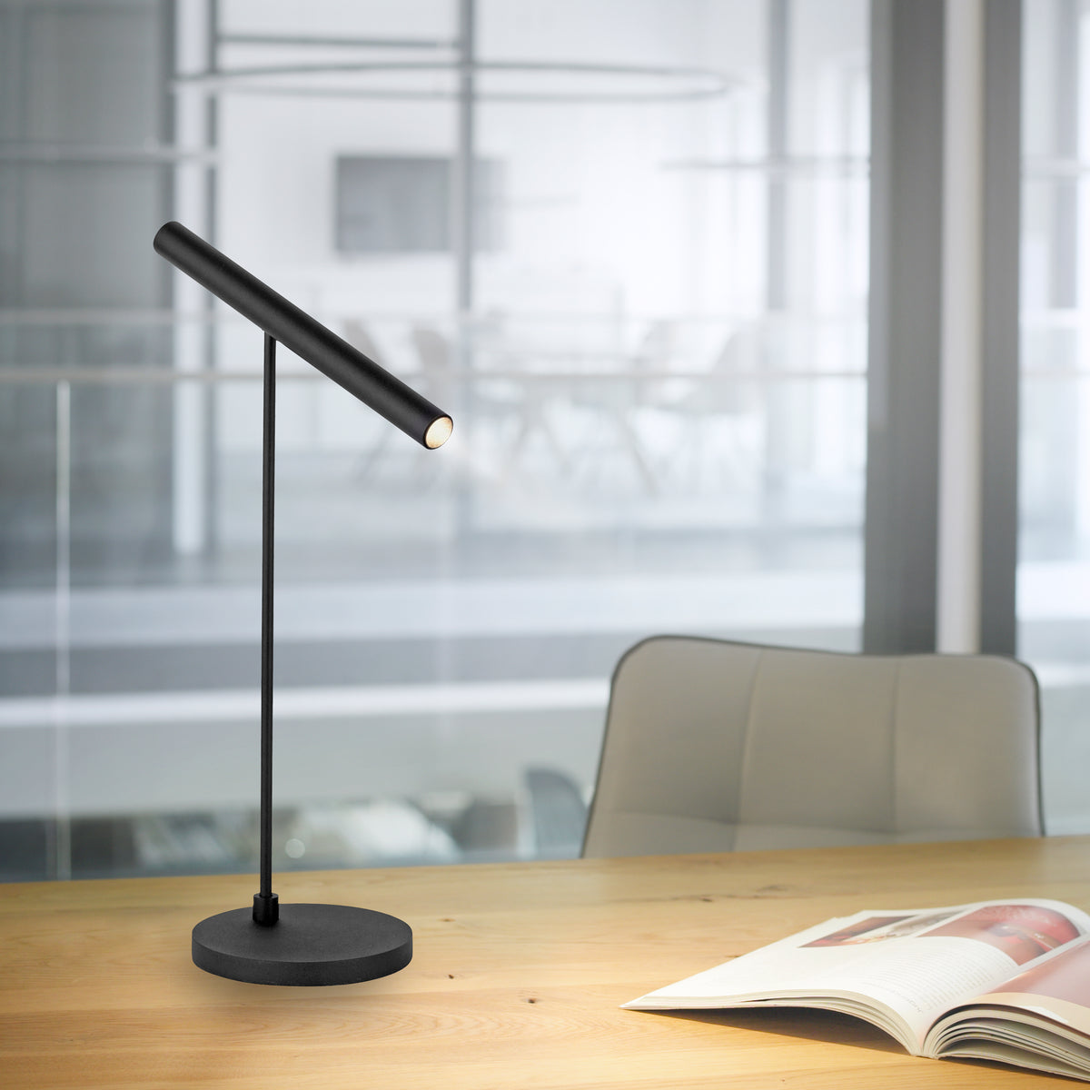 Mise en ambiance : lampe posée sur bureau en bois près d'un livre ouvert.