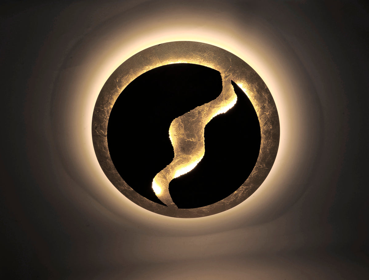 Luminaire allumé dans l'obscurité, halo lumineux doré sur support sombre.