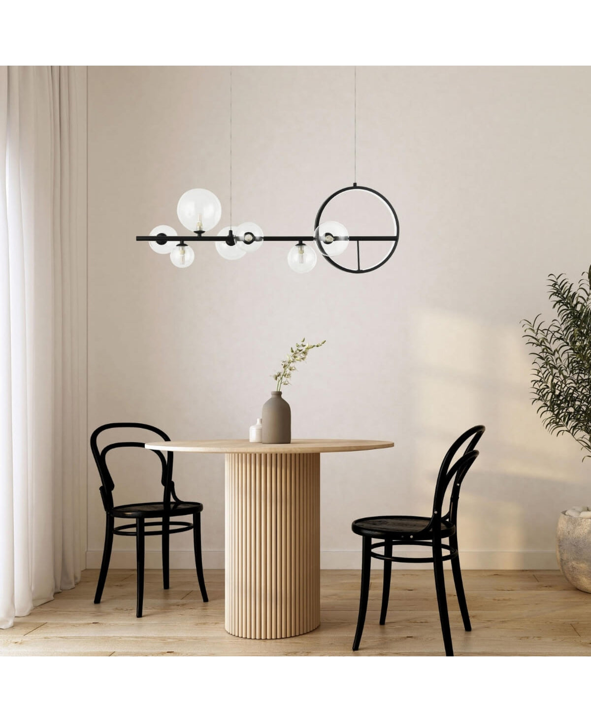 Suspension noire et globes en verre au-dessus d'une table ronde en bois clair.