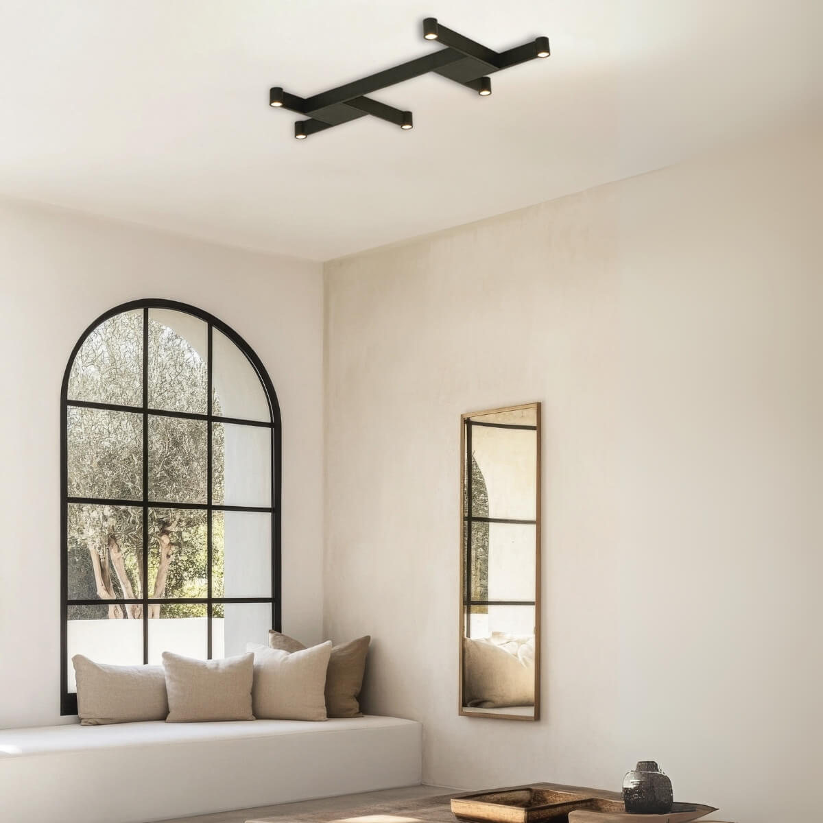 Vue rapprochée du plafond, luminaire croix noire allumé au-dessus d'une pièce épurée.