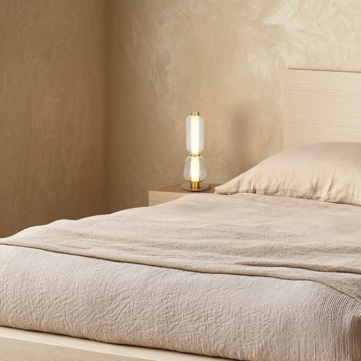 Plan large montrant la lampe sur table de nuit et lit en lin froissé