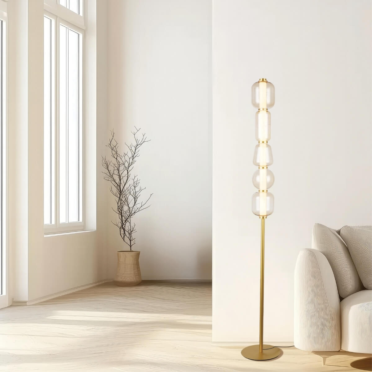 Vue large d'un salon clair avec le lampadaire doré allumé près d'un canapé beige.