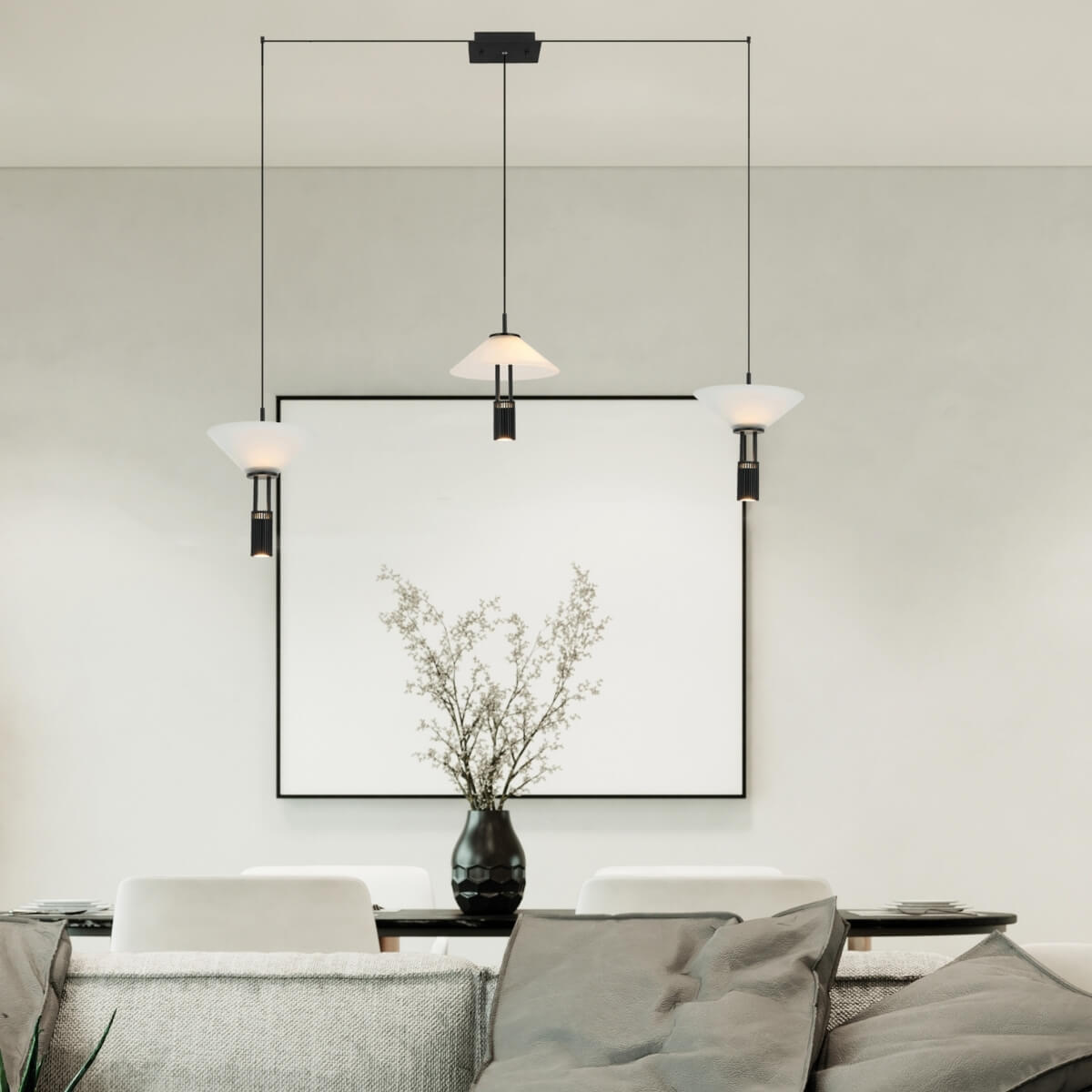 Vue rapprochée des trois lumières suspendues devant un cadre blanc et un vase.