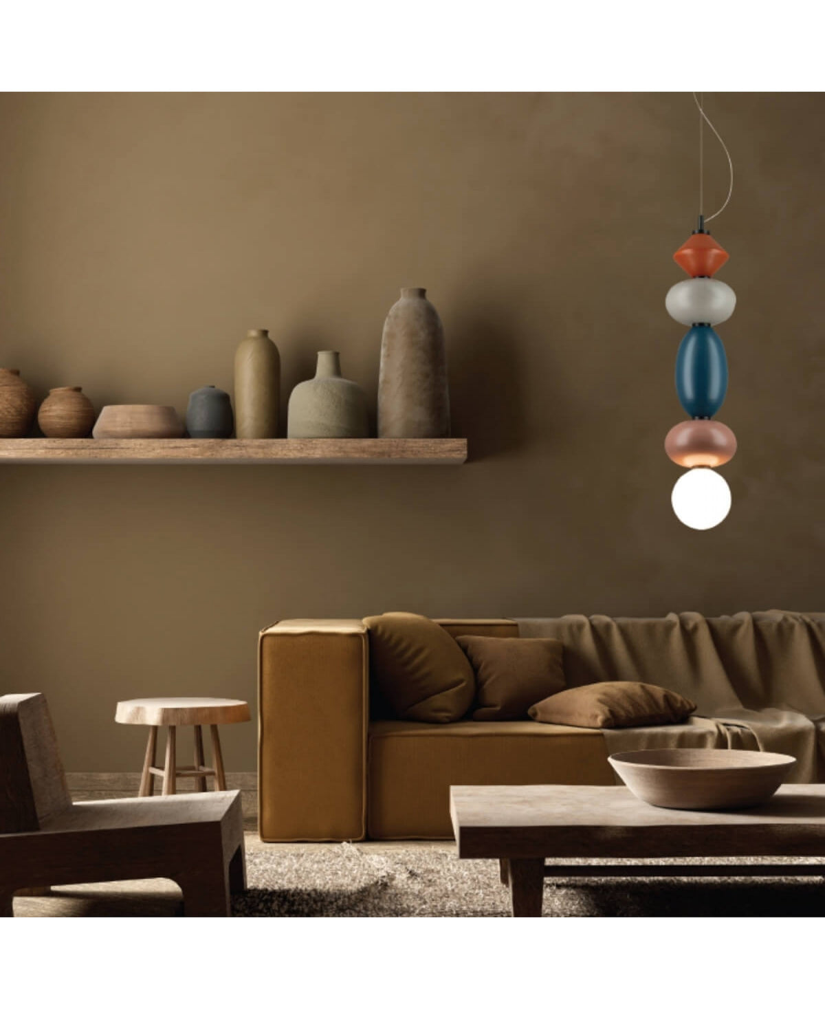 Même intérieur chaleureux, vue large montrant la suspension colorée au-dessus du canapé moutarde